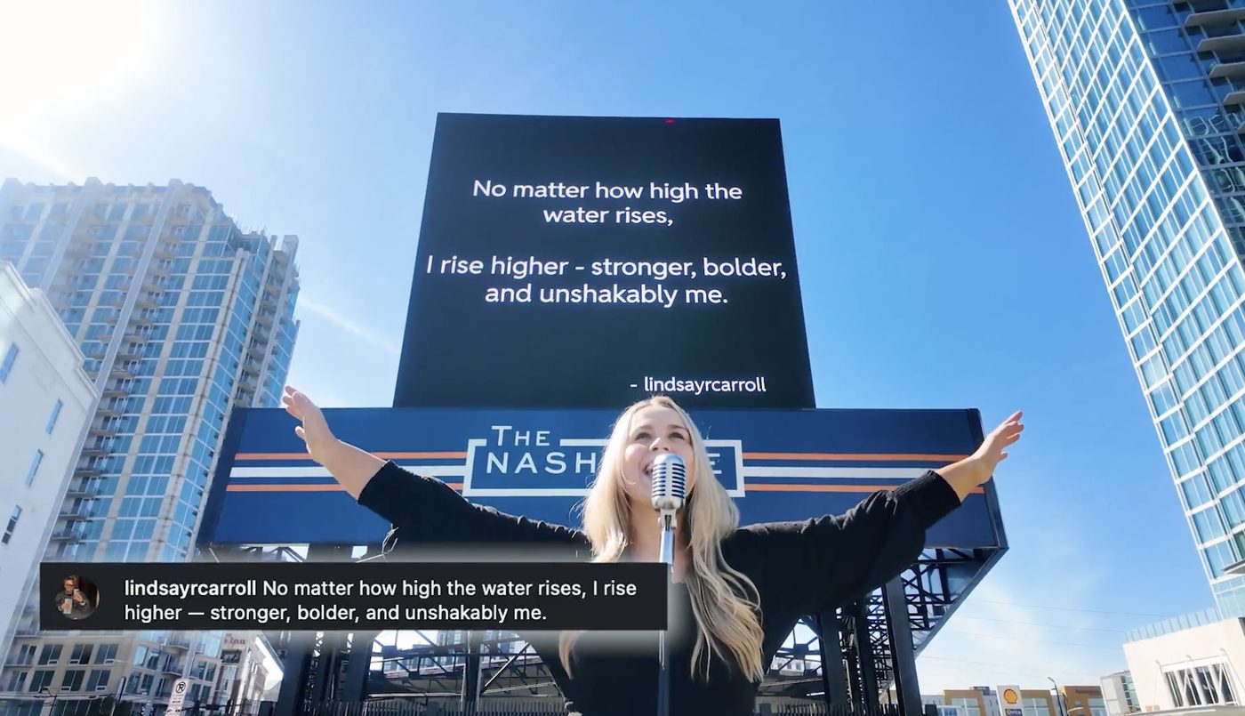 Breanna Nix singing beneath her billboard quote in downtown Nashville.