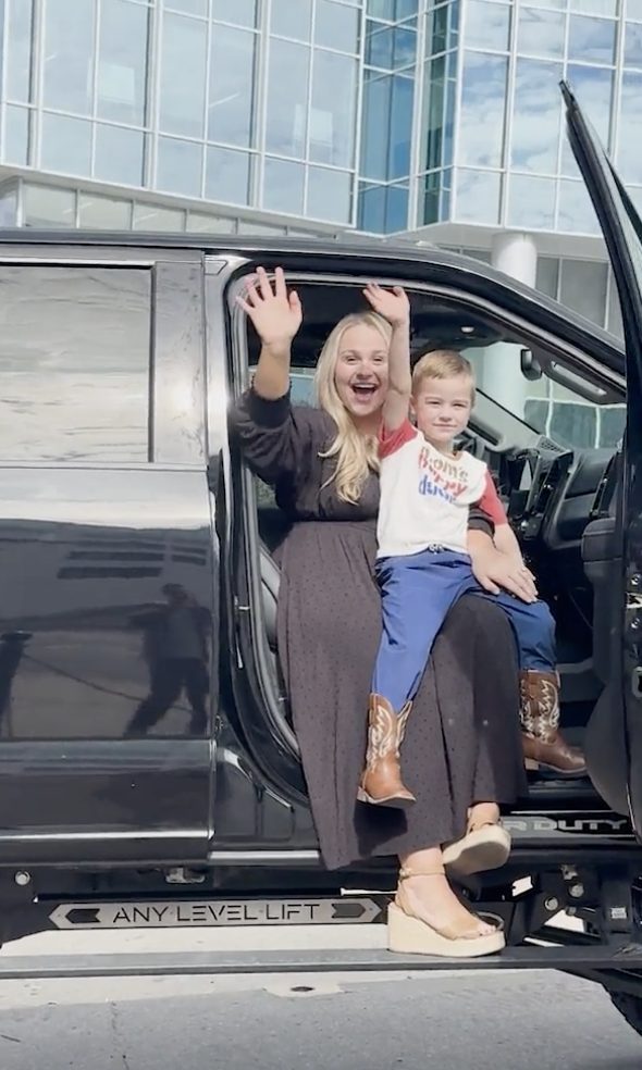 Breanna Nix waving from a truck with a child before the activation.